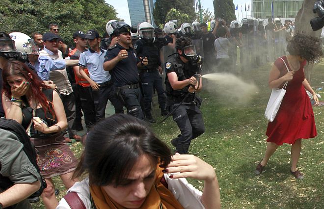 Turkish riot policeman uses tear gas against woman as people protest against destruction of trees in park in Istanbul